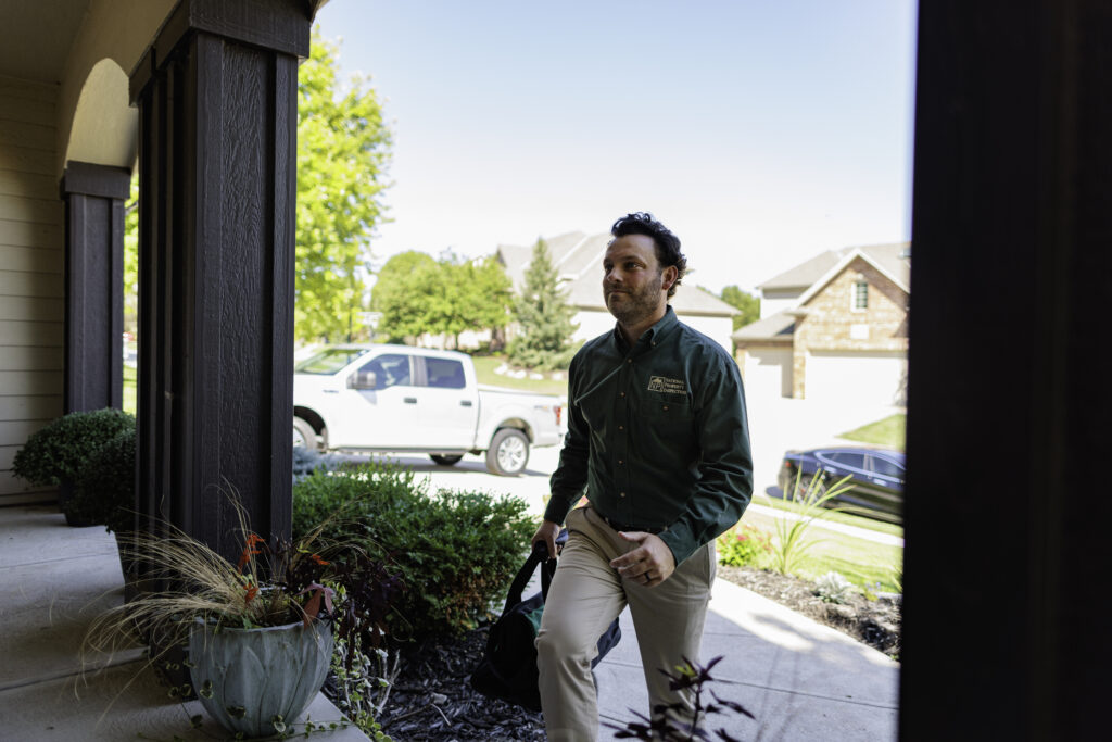 Confident home inspector enters building with work vehicle in background