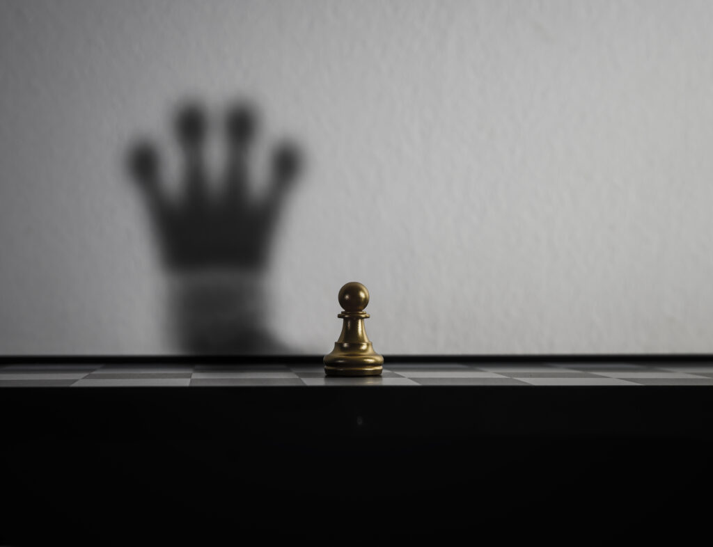 A pawn chess piece projects a shadowed silhouette of a queen chess piece, symbolizing a growth mindset.