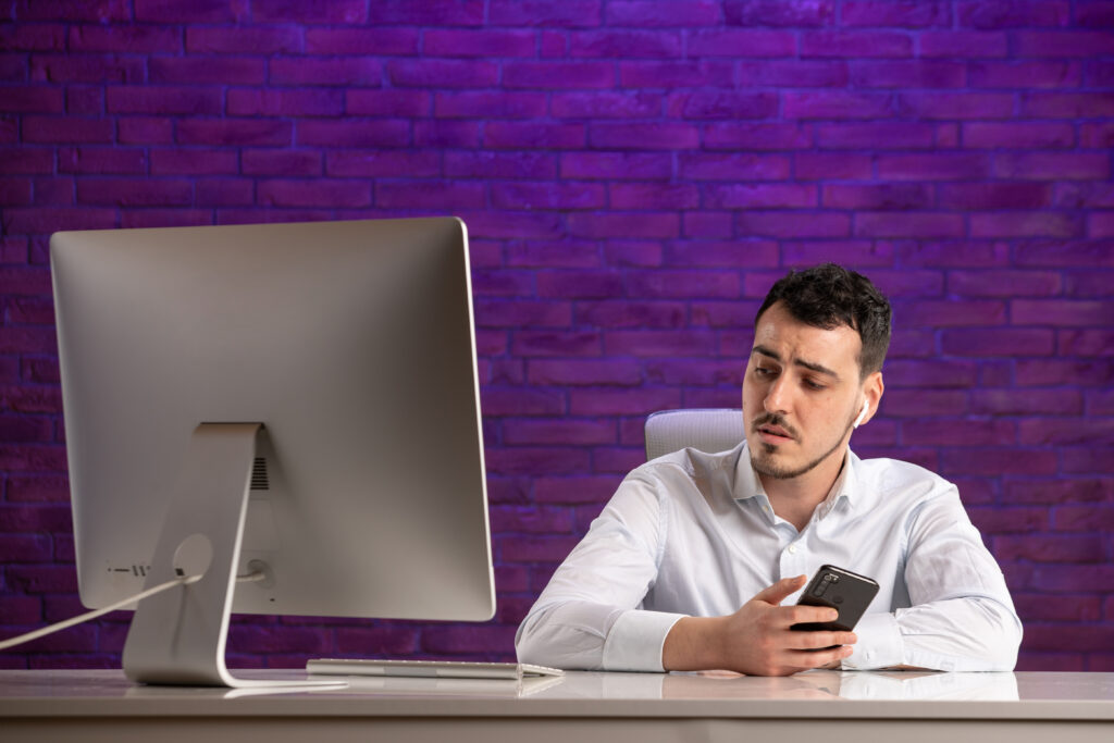 A young man looks at his computer monitor suspiciously, as though he has made an email marketing mistake.